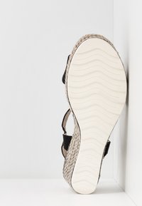 Sandale espadrille noire avec une semelle en jute tissée et une semelle en caoutchouc texturé, taille indiquée 37, avec des sangles réglables.