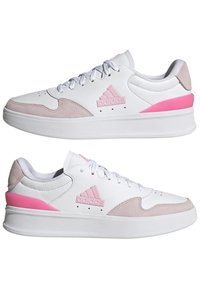 Sneakers bianchi in pelle con dettagli in suede rosa, dotati di una suola in gomma testurizzata, lacci bianchi e un logo impresso sul lato.