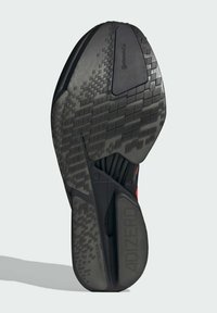 Sort atletisk sko ydersål med et tekstureret gummidesign, der har et mønster af firkanter og en mærket sektion mærket "ADIZERO."