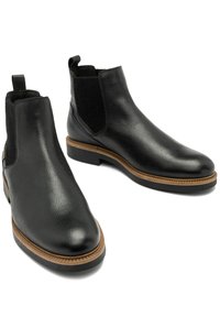 Czarne skórzane botki Chelsea o gładkim wykończeniu, z elastycznymi bocznymi panelami i brązową gumową podeszwą z teksturowanym wykończeniem.