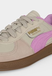 Μπεζ και ροζ αθλητικό παπούτσι Puma Palermo με μπεζ κορδόνια, χρυσό λογότυπο Puma και καφέ υφασμένη σόλα σε λευκό φόντο.