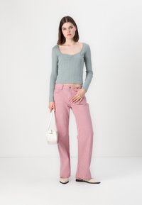 Vaaleansininen ribatut pitkät hihattaiset paita, jossa on avara kaula-aukko, yhdistettyinä vaaleanpunaisiin ja valkoisiin raidallisiin leveisiin housuihin. Pitää valkoista käsilaukku.