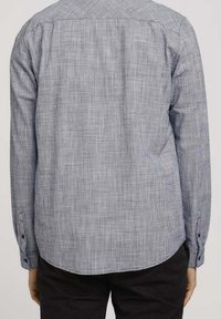 Camisa de botones a cuadros en navy y blanco, de mangas largas con puños de botón, con detalle de yugo en la parte posterior y dobladillo curvado. Hecha de tela tejida.