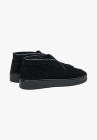 Czarne zamszowe buty za kostkę o gładkiej fakturze, z zaokrąglonym noskiem i kontrastującą czarną gumową podeszwą. Minimalistyczny design bez widocznych sznurówek.