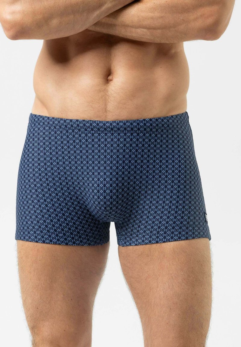 Marineblaue Boxershorts mit einem geometrischen Muster in Hellblau. Hergestellt aus dehnbarem Stoff, sitzen sie eng anliegend und haben einen elastischen Bund.