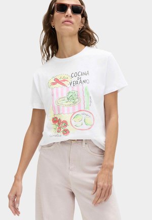 Vrouw met een zonnebril en een wit T-shirt met kleurrijke voedselillustraties en Spaanse tekst "Cocina de Verano."