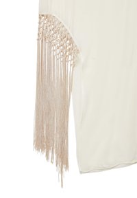Blouse couleur crème avec des franges beiges longues au niveau des manches, présentant une texture lisse et un design décontracté.