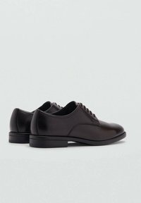Black leather shoes with a smooth finish, rounded toe, and lace-up design. Features a low heel and minimalist stitching detail.