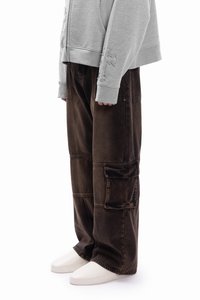 Barna cargo nadrág laza fazonnal, több zsebbel és látható varrási részletekkel. Világosszürke kapucnis pulóverrel párosítva.