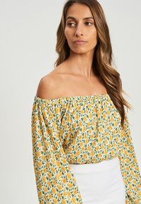 Blusa scollata con stampa floreale gialla e verde, con maniche a puff e vita arricciata, realizzata in tessuto leggero.