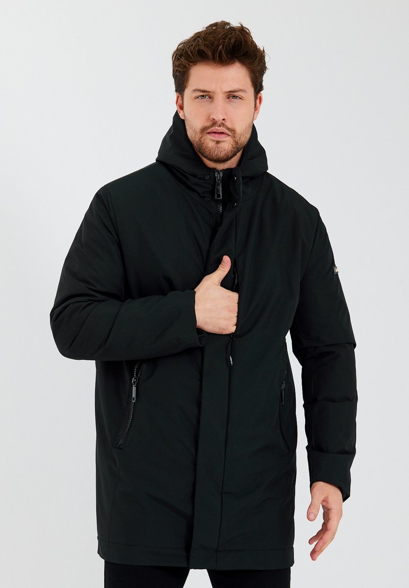 Zwarte donzenjas met capuchon, volledige ritssluiting aan de voorkant, zijzakken en een verstelbare sluiting. Soepele textuur en ontwerp tot aan de knieën.