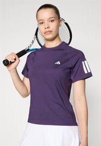 Paarse sport t-shirt met korte mouwen, voorzien van een klein wit logo op de borst en twee witte strepen op de mouw. Gelaagd, soepel stof.