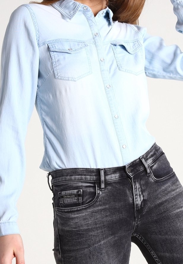 Ljusblå denimskjorta med långa ärmar, spetsig krage och två bröstfickor. Matchad med mörkgrå smala jeans med framfickor.