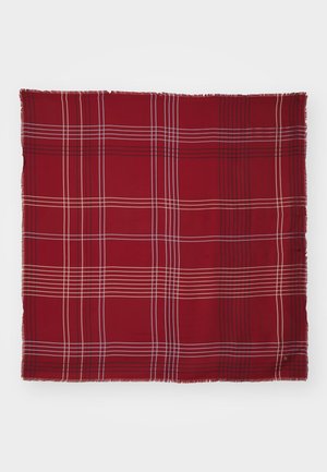 Écharpe carrée rouge avec des lignes à carreaux blanches, noires et beige, aux bords frangés, posée à plat sur un fond blanc.