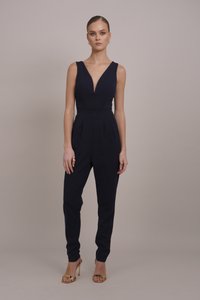 Marine jumpsuit med dyp V-hals, ermeless design og smale bukser. Har folder i midjen, accessorert med gullsandaler.
