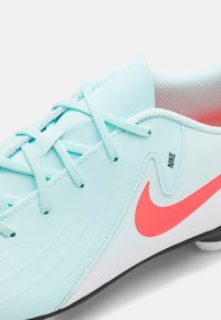 Világoskék focicipők texturált felszínekkel, fehér talppal, rózsaszín Nike logóval és hozzáillő fűzőkkel, légáteresztő hálós belső résszel.