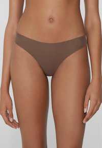 Braun nahtloser Bikiniunterteil mit weicher Textur, tiefer Schnittform und minimaler Bedeckung. Verfügt über einen glatten Taillenbund für hohen Tragekomfort.