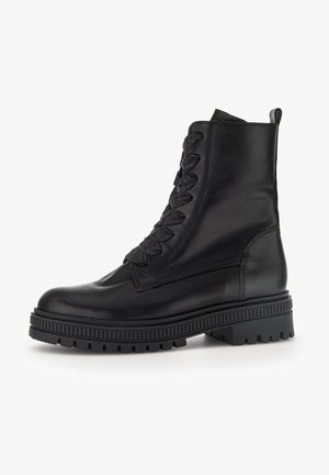 Czarne skórzane botki za kostkę z wysoką cholewką, teksturowanymi czarnymi sznurowadłami oraz masywną, żebrową gumową podeszwą. Posiadają pętelkę z tyłu.