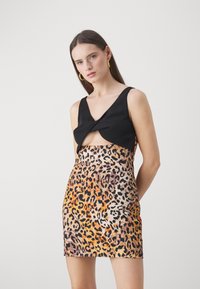 Crna kratka majica ima uvrnut dizajn, u kombinaciji s mini suknjom leopard uzorka u narančastoj i smeđoj boji. Glatka tekstura, uski kroj.
