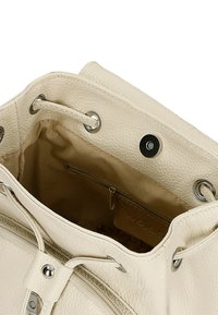 Crème-kleurige leren tas met een gestructureerd oppervlak, voorzien van zilverkleurige hardware, een trekkoordsluiting en een binnenzak met rits.