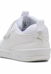 Baskets blanches avec un extérieur en cuir lisse, un col rembourré, des détails texturés et un logo subtil sur le talon. Fermeture velcro.