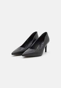 Černé lakované kožené lodičky s špičatou špičkou a elegantním, hladkým povrchem. Mají střední jehlový podpatek pro větší výšku.