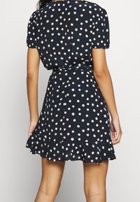 Námořnické šaty s bílými puntíky, krátké nabírané rukávy, opásaný pas a volánkový lem. Vyrobené z lehké látky s hladkým povrchem.