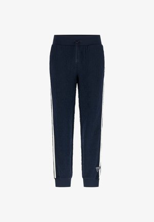 Navyblauwe joggers met een reliëf herhalend logo-patroon, witte zijstrepen, een trekkoord in de taille, afgeknipte enkels en een kleine driehoekige merkpatch nabij de zoom.