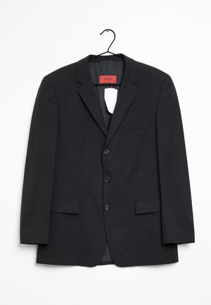 Black three-button men's blazer with notched lapel, flap pockets, and red "Hugo" label hanging on a black hanger.