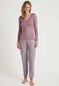 Licht paarse lange mouw top met kantafwerking, gecombineerd met pyjama broek met een geometrische print en ribbel manchet bij de enkels.