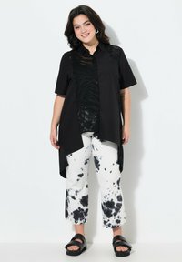 Zwarte overhem shirt met korte mouwen, met een zebra patroon. Gecombineerd met witte en zwarte tie-dye cropped broeken en zwarte sandaaltjes.