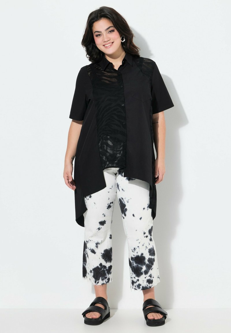 Zwarte overhem shirt met korte mouwen, met een zebra patroon. Gecombineerd met witte en zwarte tie-dye cropped broeken en zwarte sandaaltjes.
