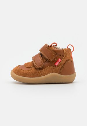 Chaussure pour enfant en cuir et suède marron avec deux brides Velcro, semelle en caoutchouc et un onglet d'accent orange. Conception à tige basse pour le confort.