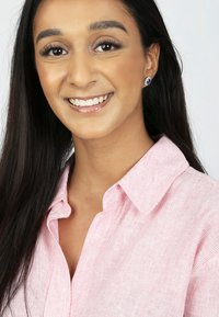 Chemise à rayures roses et blanches à boutons avec un col. Le modèle porte des boucles d'oreilles en stud. Texture lisse et lignes épurées sont des caractéristiques notables.