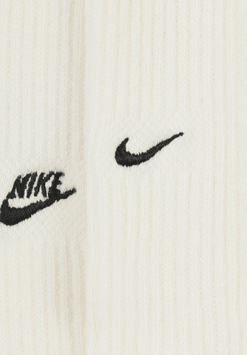 Białe skarpetki z prążkowanym wzorem z czarnym haftowanym logo "Nike" oraz charakterystycznym znakiem suda. Miękka tekstura i klasyczny design, idealne na co dzień.