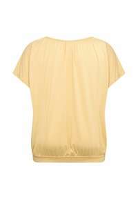 Žlutý top s krátkým rukávem a nařaseným výstřihem a elastickým spodním lemem. Hladká, lehká látka s volným střihem a minimalistickým designem.