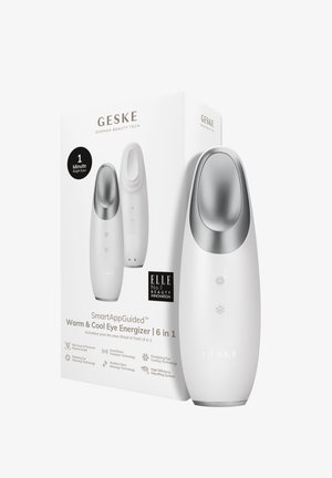 Vit handhållen enhet med silverdetaljer, som har en rund form, användargränssnittsknappar och en förpackningslåda märkt med produktinformation.