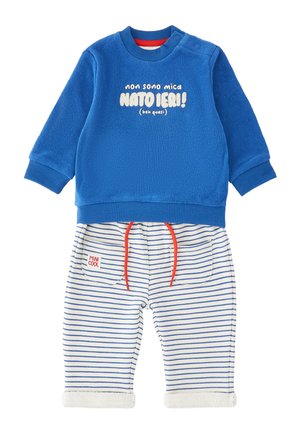 Felpa blu a maniche lunghe con testo italiano e pantaloni bianchi con strisce blu, cordini rossi e toppa con la scritta "MINI COOL."
