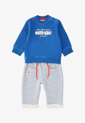 Felpa blu a maniche lunghe con testo italiano e pantaloni bianchi con strisce blu, cordini rossi e toppa con la scritta "MINI COOL."