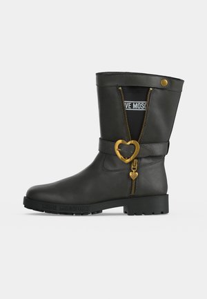 Botte noire mi-mollet avec boucle en forme de cœur dorée et fermeture éclair, marquée "Love Moschino" sur la semelle et à l'intérieur de la tige.