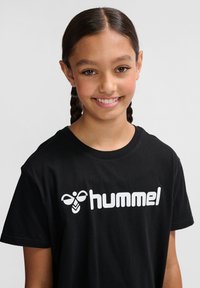 Tricou din bumbac negru cu mâneci scurte, având imprimat pe față logo-ul alb "hummel". Textură netedă și croială casual.