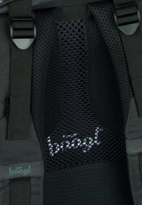 Pannello in rete nera con cuciture visibili e logo, circondato da robusti cinturini in tessuto e un materiale liscio e testurizzato in una tonalità scura.