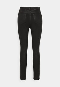 Jeans negros ajustados con una textura suave y elástica. Presenta dos bolsillos traseros con un diseño sutil y costuras minimalistas a lo largo de la cinturilla.