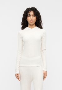 Λευκή μακρυμάνικη μπλούζα με κουκούλα και κάθετη ριμπ υφή, με εφαρμοστή σχεδίαση και διακριτική διακοσμητική  λεπτομέρεια με λογότυπο στο τελείωμα.