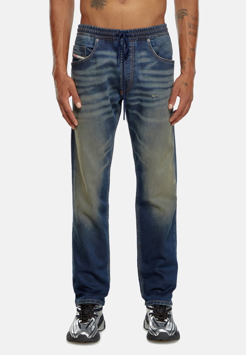 Pantalons joggers en denim avec taille élastique, couleur bleu délavé, deux poches avant et une coupe ajustée au niveau des chevilles.