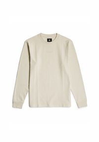 Long-sleeve, light beige ribbed t-shirt with a round neckline and subtle branding at the chest. Soft texture and relaxed fit.