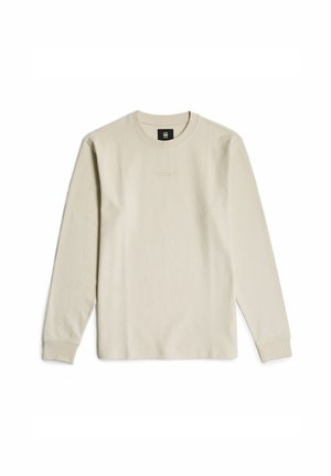 Langärmliges, hellbeiges, geripptes T-Shirt mit Rundhalsausschnitt und dezenter Markenlogo auf der Brust. Weiche Textur und bequeme Passform.