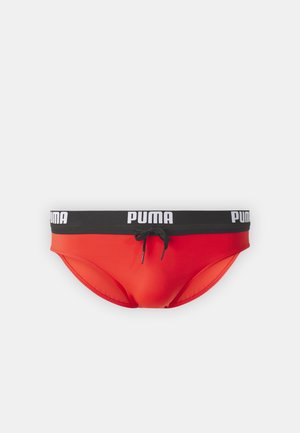 Rote Schwimmslips mit einem schwarzen elastischen Bund, der das weiße "PUMA"-Logo und einen Kordelzug aufweist. Hergestellt aus glattem, dehnbarem Stoff.