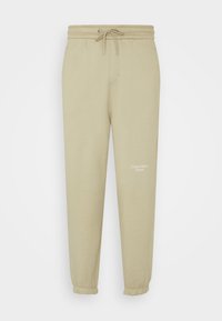 Ljusbeige sweatpants med elastisk midja, justerbar snörning och muddar. Har en liten vit logotyp på vänster lår.