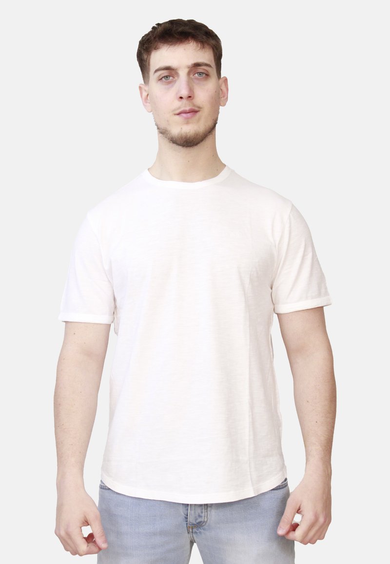 T-shirt grigio chiaro a maniche corte realizzata in tessuto morbido, con scollo rotondo e un'orlo posteriore leggermente più lungo, indossata con jeans blu.